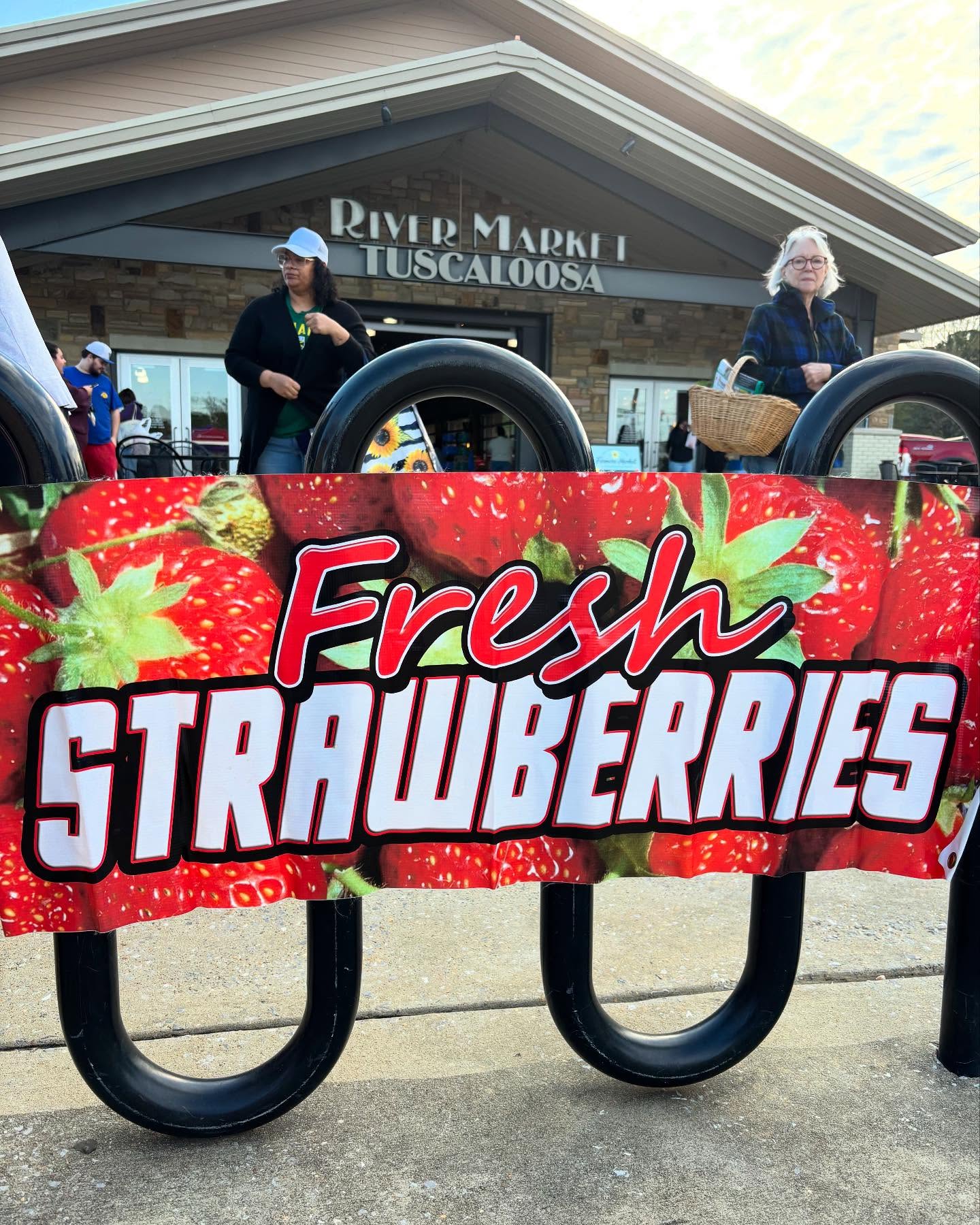 Tuscaloosa River Market with Fresh Strawberries Banner and two shoppers.